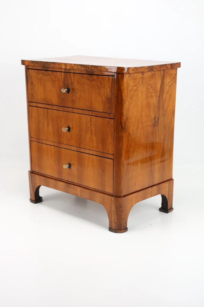 An antique South German chest of drawers from circa 1825 in walnut veneer on solid pinewood demonstrates the regional character precisely.